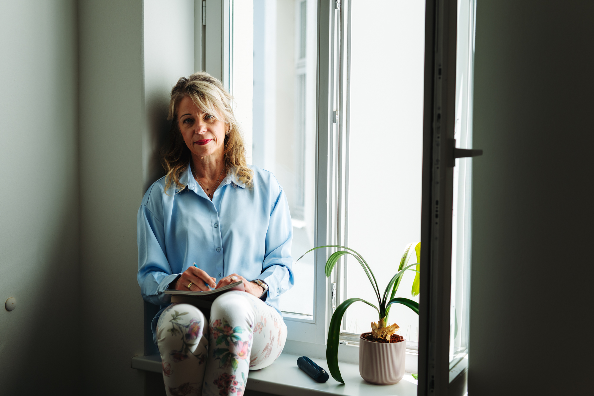 Cornelia Mühlberg Coach Cornnelia Mühlberg auf einer Fensterbank beim Gespräch